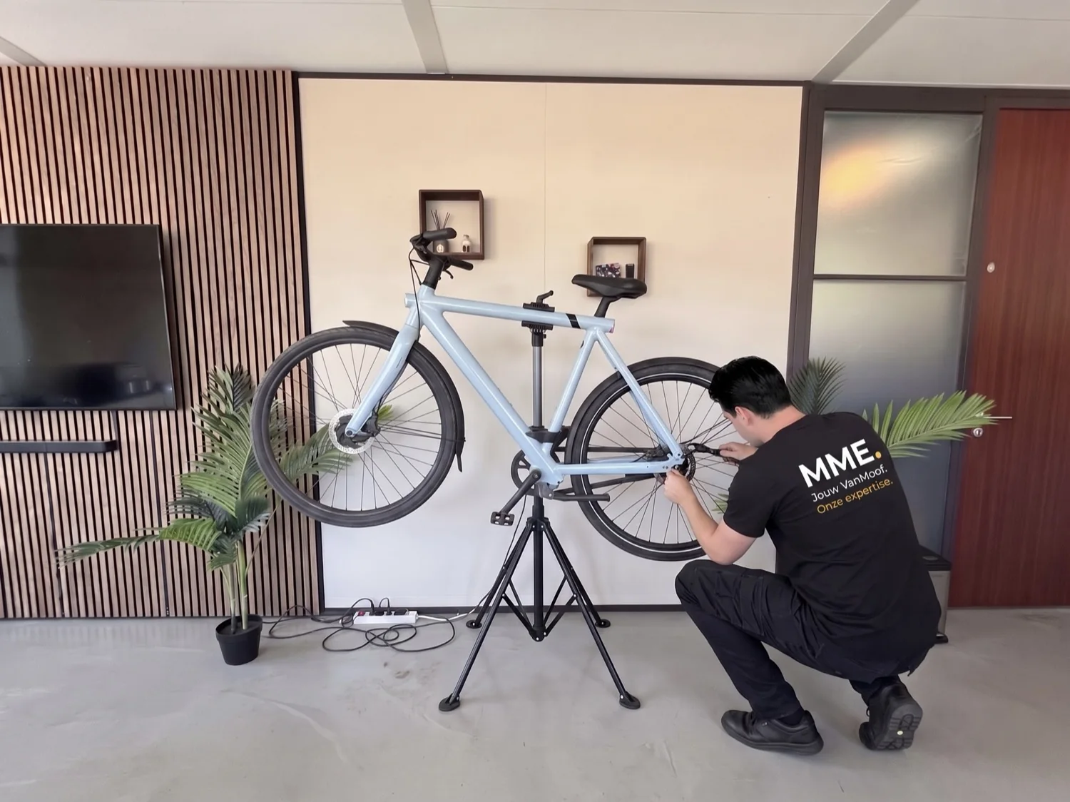 Monteur werkt aan een blauwe VanMoof op de reparatiestandaard in onze werkplaats